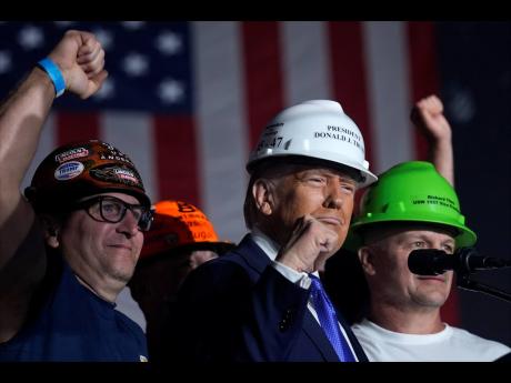 Donald Trump stands on stage with steelworkers as he speaks during a campaign rally at Arnold Palmer Regional Airport.