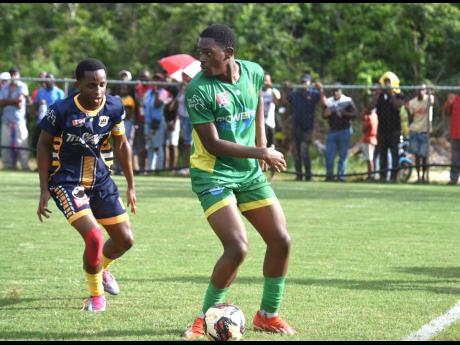 Ocho Rios High’s Robert Morris (right) shields the ball from Munro College’s Triston Forde  during their ISSA/WATA daCosta Cup quarter-final clash at Munro College yesterday. The game ended in a 1-1 draw.
