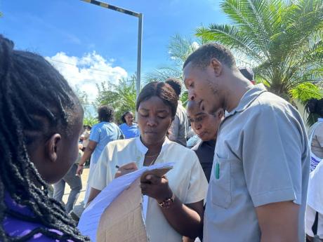 Some staff members of Secrets and Breathless resorts in Montego Bay, St James, sign a National Workers’ Union form during a protest on Tuesday.