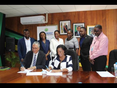 Vivion Scully (seated at left), CEO, Agro-Invest Corporation, and Donna Marie Howe (seated at right), managing director, Jamaica Bauxite Mining, sign the memorandum of understanding while (standing from left) Phillip Garvin, Dahlia Dwyer Hodelin, Keisha Sc
