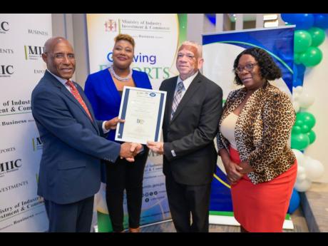 Minister of Industry, Investment and Commerce Senator  Aubyn Hill (left), and Manager, National Certification Body of Jamaica (NCBJ), Navenia Wellington Ford (second left), present a certificate to Registrar, Department of Cooperatives and Friendly Societi