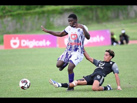 Credit: Ricardo Makyn Kingston College’s Kimani Reece attempts to dribble away from the sliding challenge of Mona’s Alex Suazo during their ISSA Manning Cup quarterfinal game at the Stadium East Sports Complex yesterday.
