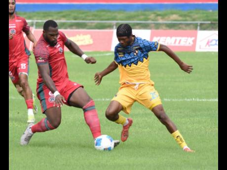 Montego Bay United’s Josiah Trimmingham (left) and Racing United’s Tyrone Mullings go into a challenge during their Jamaica Premier League encounter at the Ferdie Neita Park yesterday.
