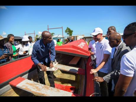 Haakon, Crown Prince of Norway (third right), looks on as Derek Osbourne, a fisherman at the Rocky Point Fishing Village in Clarendon, explains how the tracker is applied to the boat and how beneficial it has been during a tour on Monday. Former Fisheries 