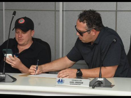 Credit: Ashley Anguin Directors of Montego Bay Multi-Sports Development Limited Max Jardim (left), and Yoni Epstein sign a document at the St James Municipal Corporation at the closing of bids to lease the Montego Bay Sports Complex yesterday.