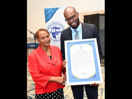 Jovan Johnson, treasurer of the Press Association of Jamaica (PAJ), presents a citation to veteran honouree, Barbara Gayle, during the PAJ Veterans’ Luncheon.