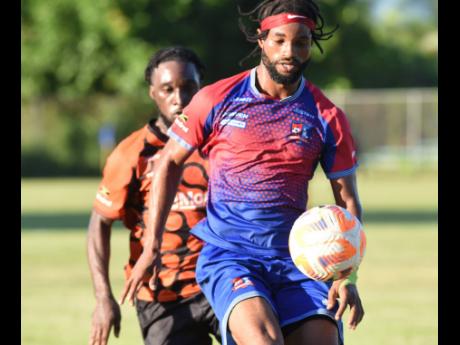 Dunbeholden’s Chevoy Watkin (right) tries to keep Tivoli Gardens’ Anthony Nelson at bay during their Jamaica Premier League encounter at the Dunbeholden Sports Complex, yesterday.