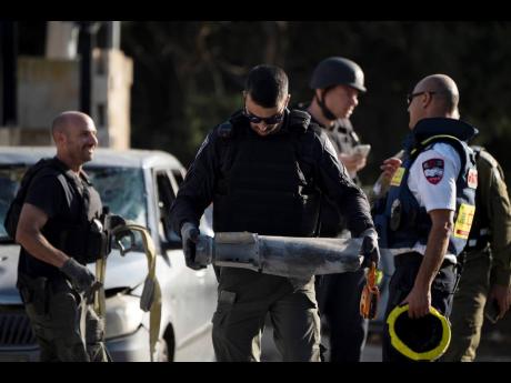 A member of the Israeli security forces carries a piece of a projectile extracted from the site where a rocket, fired from Lebanon, hit an area in the town of Nahariya, northern Israel,
