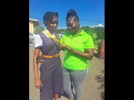 Credit: Rasbert Turner photo Mother Tracey-Ann Harriage admires daughter Kimoya Brown’s medal at Dinthill Technical High School on Thursday.