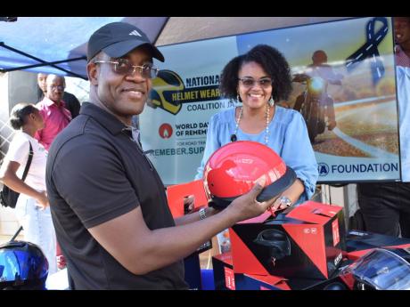Dr Kevin Blake, Commissioner of Police, gets ready to distribute helmets in Mandeville, Manchester, following a ‘ride out’ from Ferry, St Catherine, to mark World Day of Remembrance for Road Traffic Victims, recently. Looking on is Claudine Allen, gene