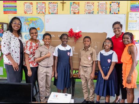 CEO of the Grace and Staff Community Development Foundation, Sandrina Davis (second right), presents a smart TV to grade-five Class 524 at St Richard’s Primary School in Kingston, on November 13. Accepting the donation are (from left): Michelle Flemming-