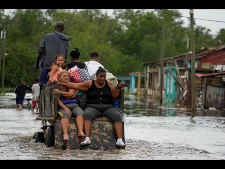 Credit: AP Residents ride through a flooded street on a horse-drawn cart after Hurricane Rafael passed through Batano, Cuba, Thursday, November 7.