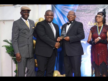 Donmayne Gyles (centre) receives his recognition award and poses for a picture with the university president, Professor Lincoln Edwards (second right). President of the NCU Alumni Federation International, Harold Clayton, and Beverly Henry, retired NCU adm
