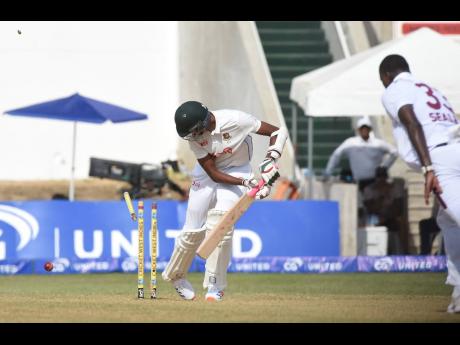 Nahid Rana (left), from Bangladesh looks back to watch his leg stump flying off the bowling of Jayden Seales (right) on the second day of the second Test match between the West Indies and Bangladesh at Sabina Park, yesterday.