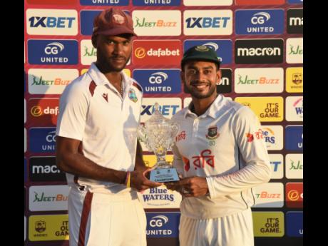 West Indies captain Kraigg Brathwaite (left) and Mehidy Hasan Miraz, the Bangladesh skipper, pose with the Champions Trophy after the two teams tied the two-match Test series on Tuesday.  Bangladesh defeated the West Indies by 101 runs on the fourth day of