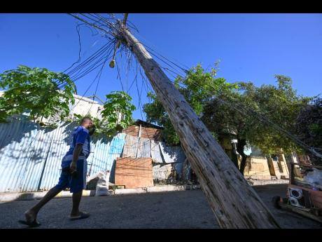 A resident walks under a leaning  lightpost on George’s lane behind the Sutton Street Court.