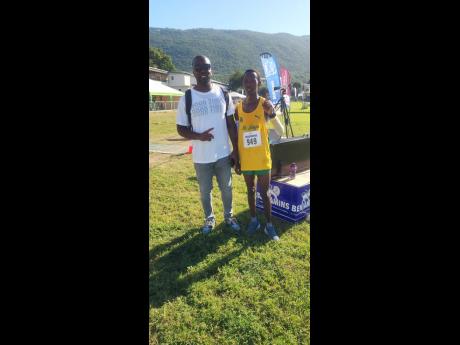 Credit: Raymond Graham Bryan Achau of, St Jago High School, poses with his coach, Davaon Spence, after his impressive victory in the boys’ 5000m Open at the Wesley Powell Benjamin track and field athletics meet at Excelsior High School yesterday. Achau clocked 15 minutes, 40.7