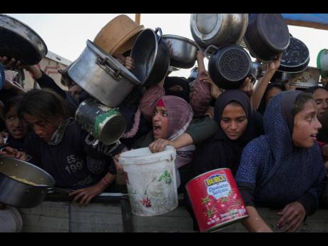 Palestinian women and girls struggle to reach for food at a distribution centre in Khan Younis, Gaza Strip, on December 6.