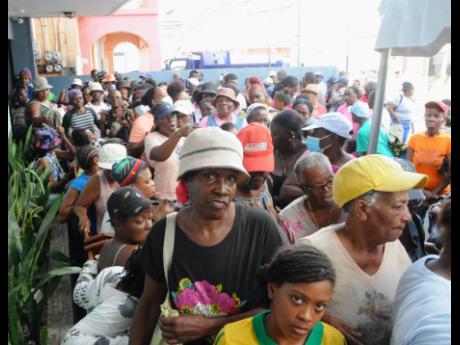 People line up to receive their Christmas food items during Madden’s Funeral Home’s annual Christmas treat at its Montego Bay location last Thursday.