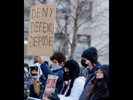 Demonstrators hold up signs while waiting for the arrival of Luigi Mangione for his arraignment in Manhattan Criminal Court, Monday, December 23, 2024, in New York. 