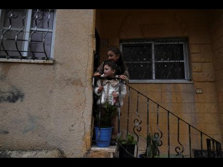 Credit: AP Palestinian girls watch the funeral of Zein Atatrah, 18, as they stand on the steps of their house in the West Bank town of Ya’bad.