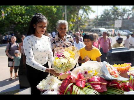Relatives of tsunami victims offer floral tributes at a memorial built in memory of those who died during the 2004 Indian Ocean tsunami as they mark the 20th anniversary in Peraliya, Sri Lanka.