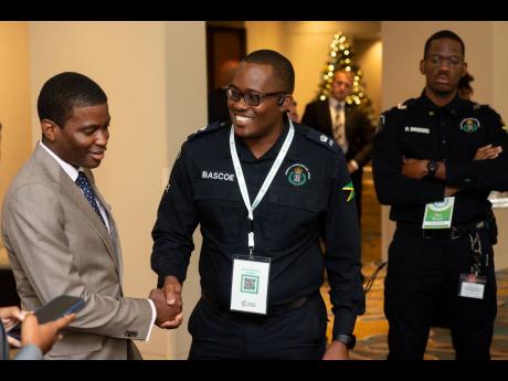PM Dickon Mitchell of Grenada at Jamaica Constabulary Force’s tech display at Connected Caribbean Summit. He is received by Superintendent Orette Bascoe of the JCF Technology Branch under as Corporal Paul Brown (right) looks on. 