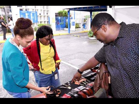 Zeelah Davis, (in front) of my Old Man Leathercraft, shows his leather items to Gabrielle Pink (left), member service representative,and Gabrielle Gibbs (right), administrative assistant, credit Administration Unit, both at JN Bank, as they check out the i