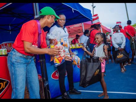 Shelly-Ann Fraser-Pryce (left), founder and chairwoman, Pocket Rocket Foundation, readies to fill the children’s goodie bags with snacks, courtesy of Excelsior Biscuit Company. Fraser-Pryce through her Foundation hosted the 17th consecutive staging of he