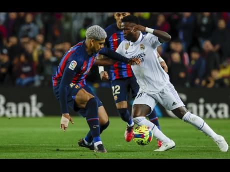 Real Madrid’s Vinícius Junior (right) and Barcelona’s Ronald Araujo fight for the ball during the Spanish La Liga soccer match between Barcelona and Real Madrid at the Camp Nou stadium in Barcelona, Spain, on March 19, 2023. 