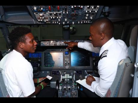 Credit: Contributed First Officer Victor Dawkins (right) introduces Saunders to a few cockpit controls, sparking excitement about his future. Although he has yet to travel outside Jamaica, the youngster dreams of exploring the world, with California topping his list.