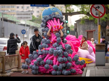 Artist Kong Ning walks along a street as she wears her latest work “Sing for the Earth” in commemoration of Earth Day in Beijing, Saturday, April 22, 2023.