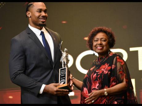 Discus thrower Rojé Stona (left) accepting the RJRGLEANER National Sportsman of the Year Award from Minister of Culture, Gender, Entertainment and Sport Olivia Grange.