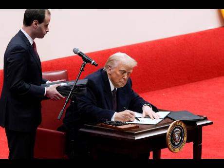 Will Scharf assists as President Donald Trump signs an executive order at an indoor Presidential Inauguration parade event in Washington on Monday.