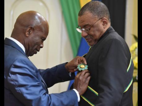 Deputy Governor General Steadman Fuller (left) pins Professor Kwame Dawes during the Ceremony of Investiture at King’s House on Wednesday.