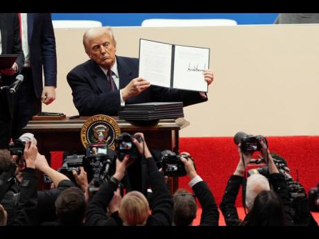 President Donald Trump holds up an executive orders after signing it at an indoor Presidential Inauguration parade event in Washington DC, January 20. 