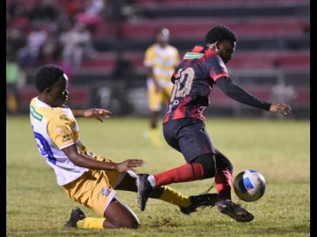 Rushike Kelson (right) of Arnett Gardens hurdles a tackle by David Hutchinson of  Molynes United during their Jamaica Premier League football match at the Anthony Spaulding Sporting Complex on Thursday night. The game ended in a 0-0 draw.