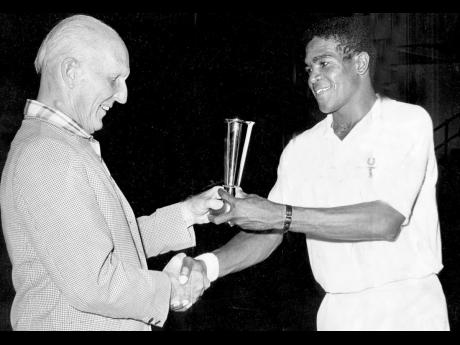Lance Lumsden (right), Jamaica’s 1966 tennis singles champion receiving his trophy for his win from Chairman of National Sports Limited, Sir Herbert McDonald at the National Auditorium. Lumsden defeated his touring partner Richard Russell 11-9, 7-5, 7-9,