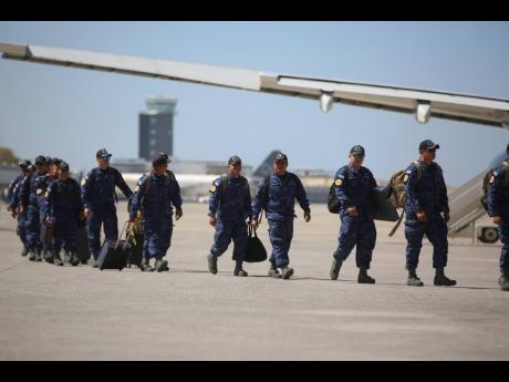Members of a UN-backed El Salvadoran police force walk on the tarmac of the Toussaint Louverture International Airport after landing in Port-au-Prince, Haiti, Tuesday, February 4, 2025. (AP Photo/Odelyn Joseph)