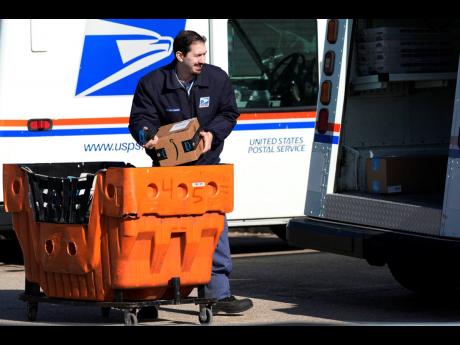 Credit: FILE - A US Postal Service employee loads parcels outside a post office in Wheeling, Illinois, on January 29, 2024. (AP Photo/Nam Y Huh, File)