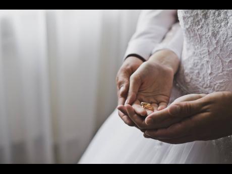 A man and a woman holding wedding rings.