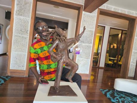 Credit: Photo by Corey Robinson Owen ‘Blakka’ Ellis poses with a metal sculpture of reggae legend Bob Marley that was unveiled at the S Hotel in New Kingston on Thursday,