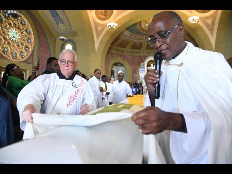 Deacon Ronald Thwaites (left) and Father Kingsley Asphall put a white pall over the coffins of Camesha and O’Neil Stevens in remembrance of their baptismal garments. It symbolises the clothing of the departed believers in Christ’s purity and beauty.