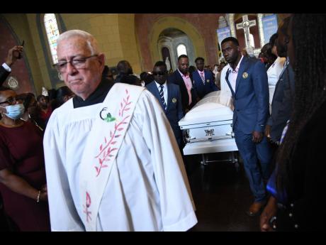 
Deacon Ronald Thwaites leads the procession after the funeral for former Jessie Ripoll Primary School Principal O’Neil Stevens, and his wife Camesha Lindsay-Stevens, a personal banker. The couple were killed in a motor vehicle crash in the  United State