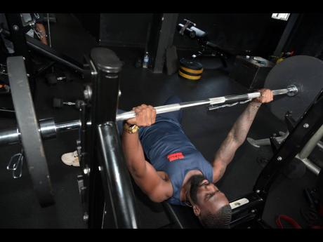  Reid performing a bench press exercise at Alpha’s Iron Den gym.
