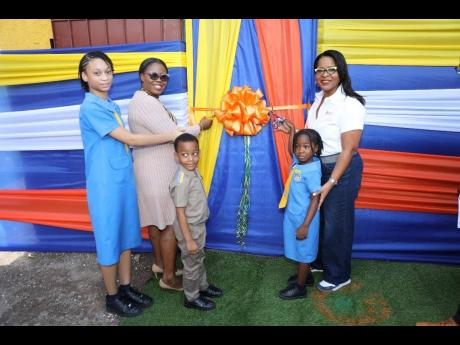 International Game Technology (IGT) Jamaica General Manager Debbie Green (right) proudly leads the ribbon-cutting ceremony to officially unveil the newly upgraded After School Advantage (ASA) Centre at Dunrobin Primary School on International Day of Educat
