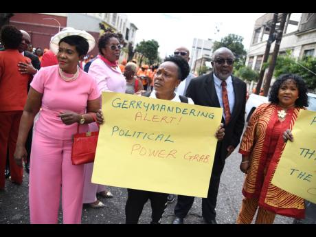 Credit: Antoine Lodge/Photographer Surrounded by opposition parliamentarians, Karen Johnson, resident of Monza in Portmore, St Catherine, holds a placard in protest of a bill being moved through Gordon House to establish Portmore as Jamaica’s 15th parish.