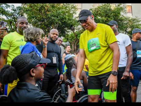 Credit: Matthew McKoy/Photographer Prime Minister Dr Andrew Holness (right) greets Sashagaye Thompson at the Sagicor Sigma Run 2025.