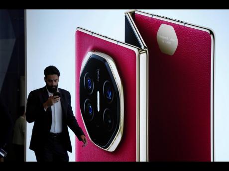 Credit: AP A man walks in front of a giant billboard display of Huawei’s industry’s first tri-foldable phone during the opening of its global sales in Kuala Lumpur, Malaysia, Tuesday, February 18, 2025.