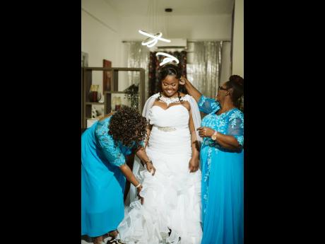 Credit: Contributed The bride adds the finishing touches with the help of her godmother Merline Cannon (left) and mother Andrea Wilson (right), just moments before her grand entrance down the aisle.